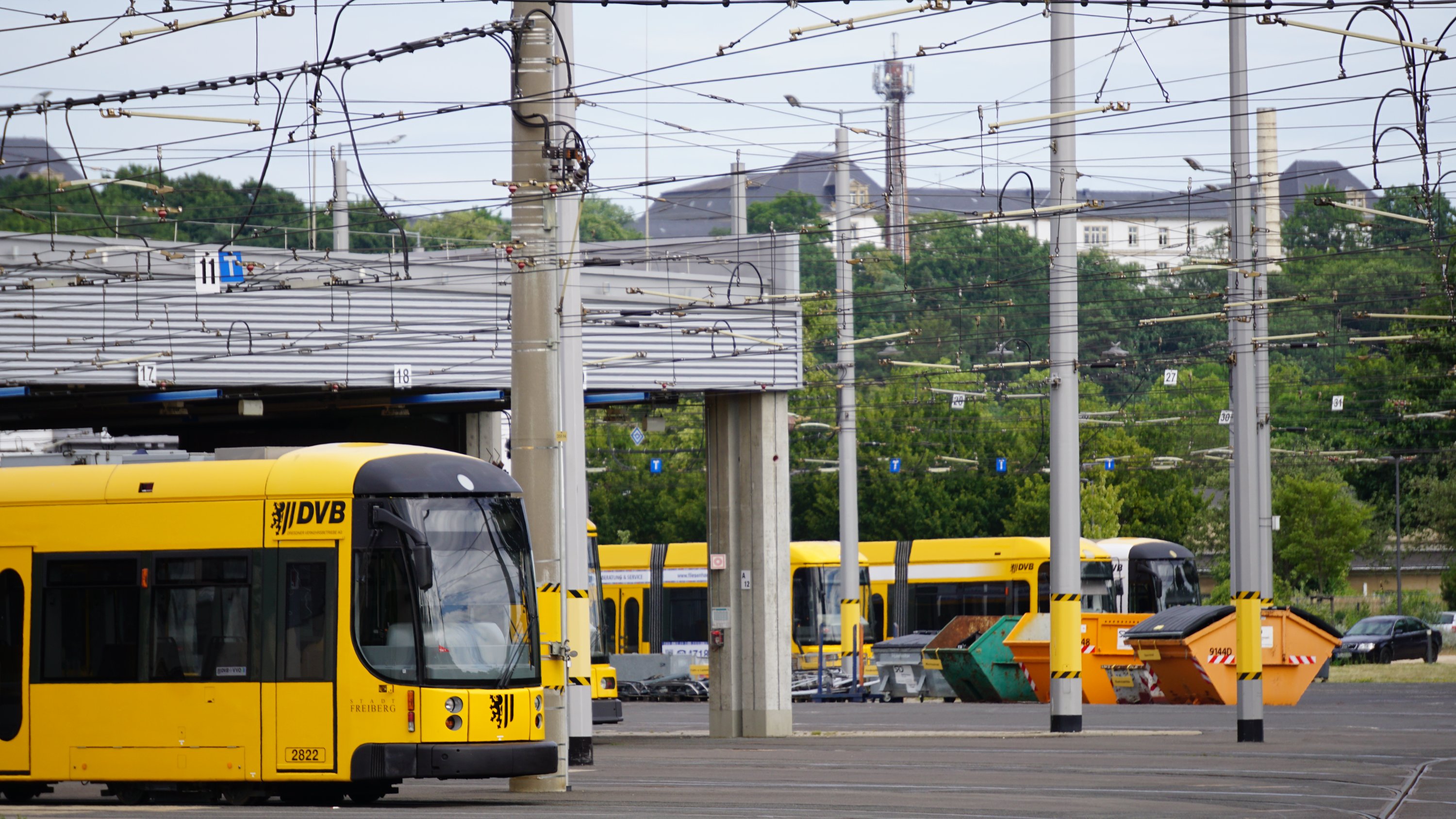 Blick über den Betriebshof 
Mehrere gelb-schwarze Straßenbahnen
ehemalige Kassernengebäude der Stauffenbergallee im Hintergrund 