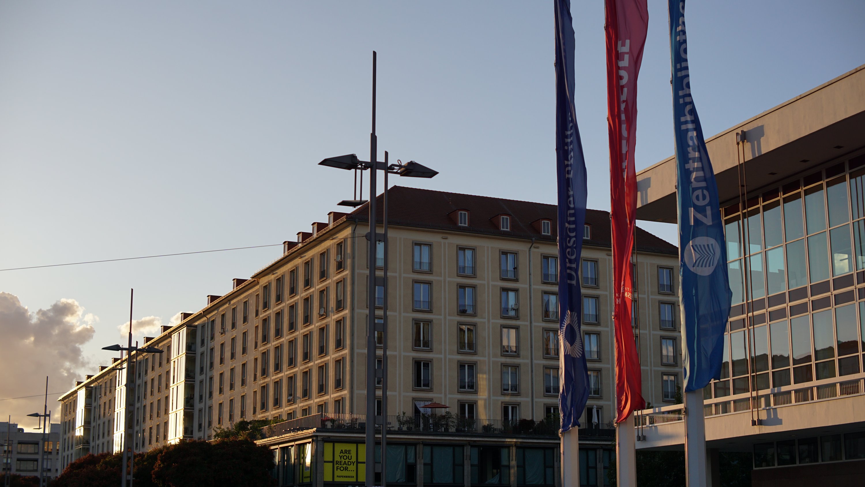 Vom Sonnenuntergang angeleuchtete Häuserfronten mit Kulturpalast und Fahnen 