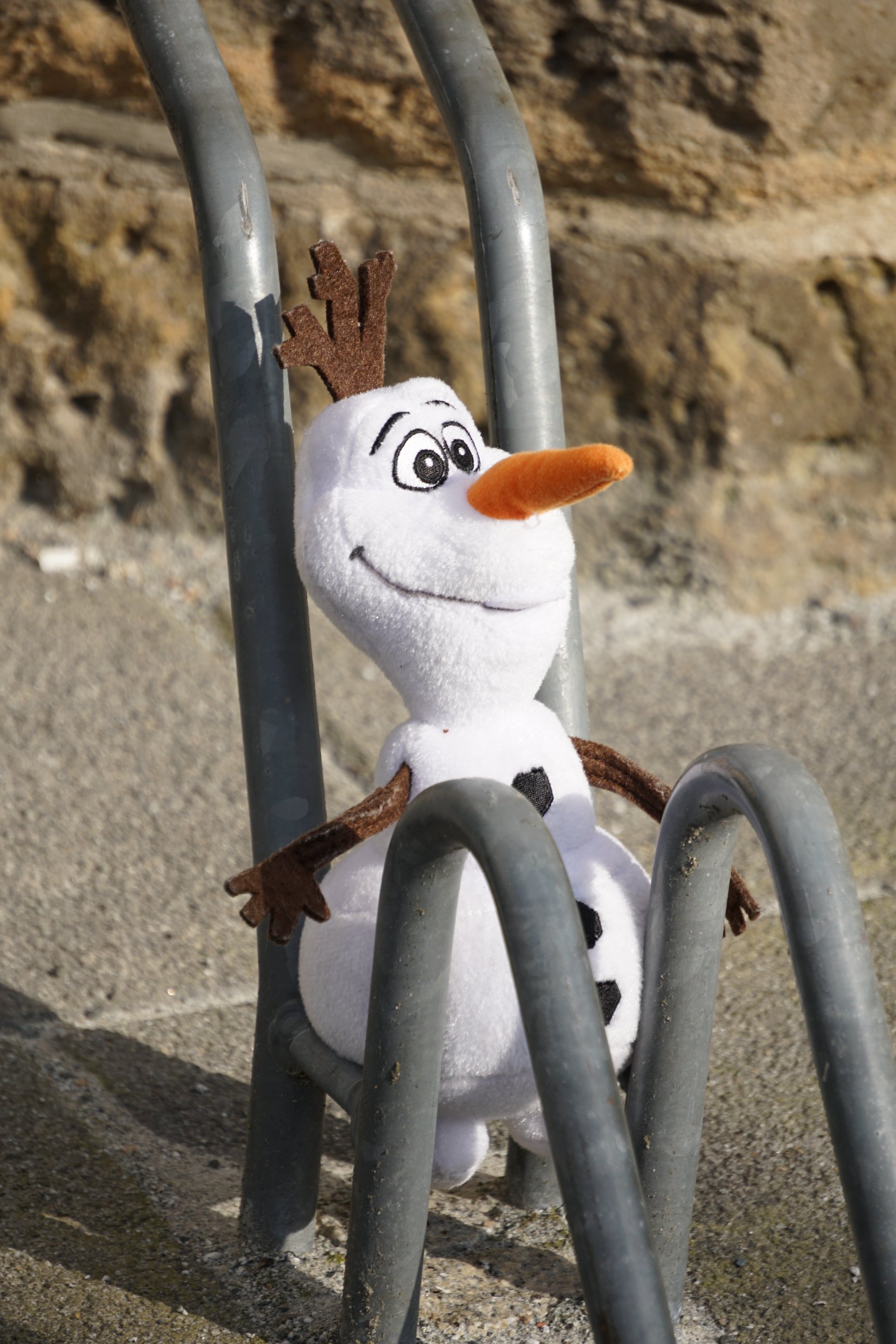 Ein Plüschtier-Schneemann steckt in einem Fahrradständer 