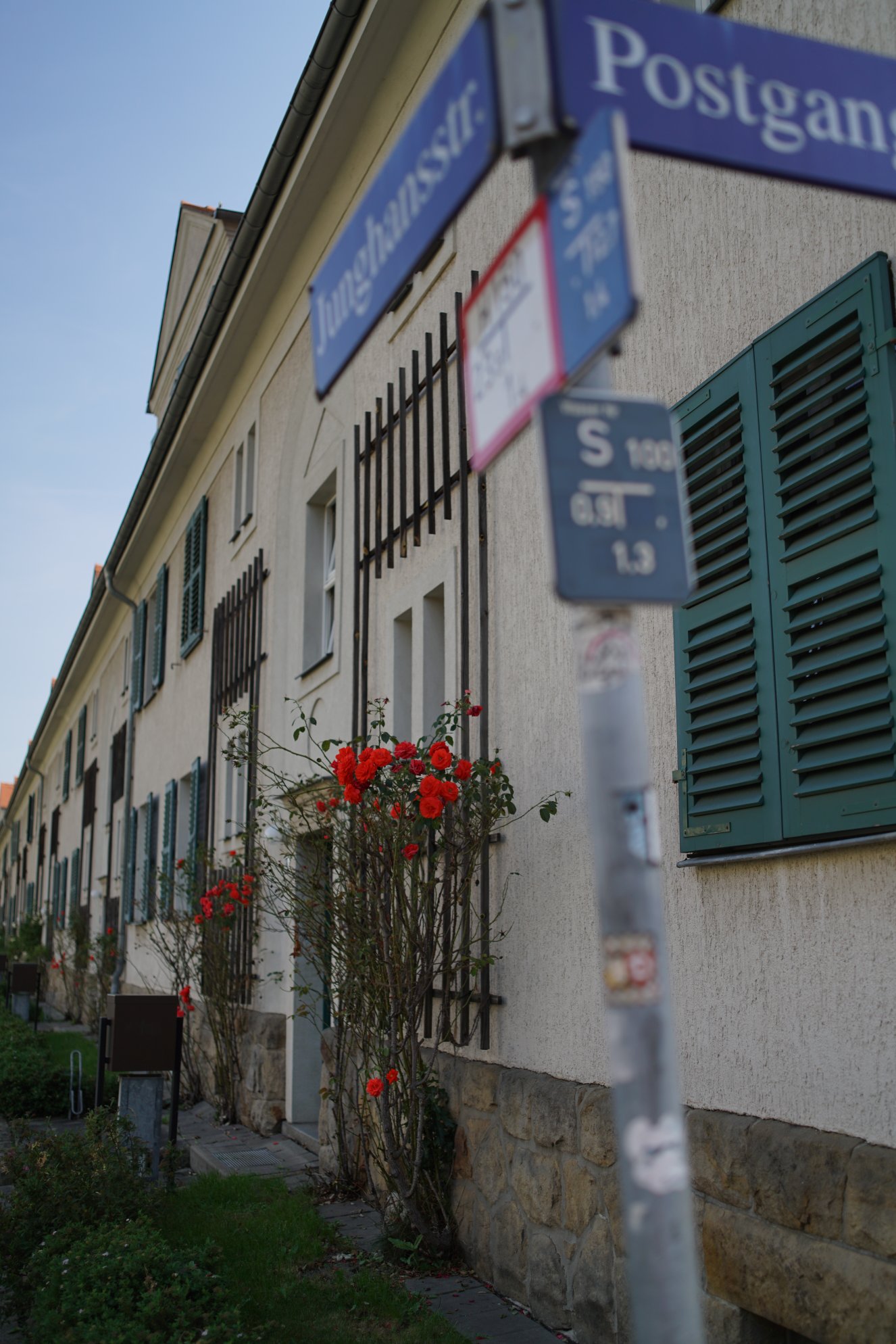 Blick von etwas weiter weg, inklusive Straßenschild im Vordergrund und mehr Fensterläden 