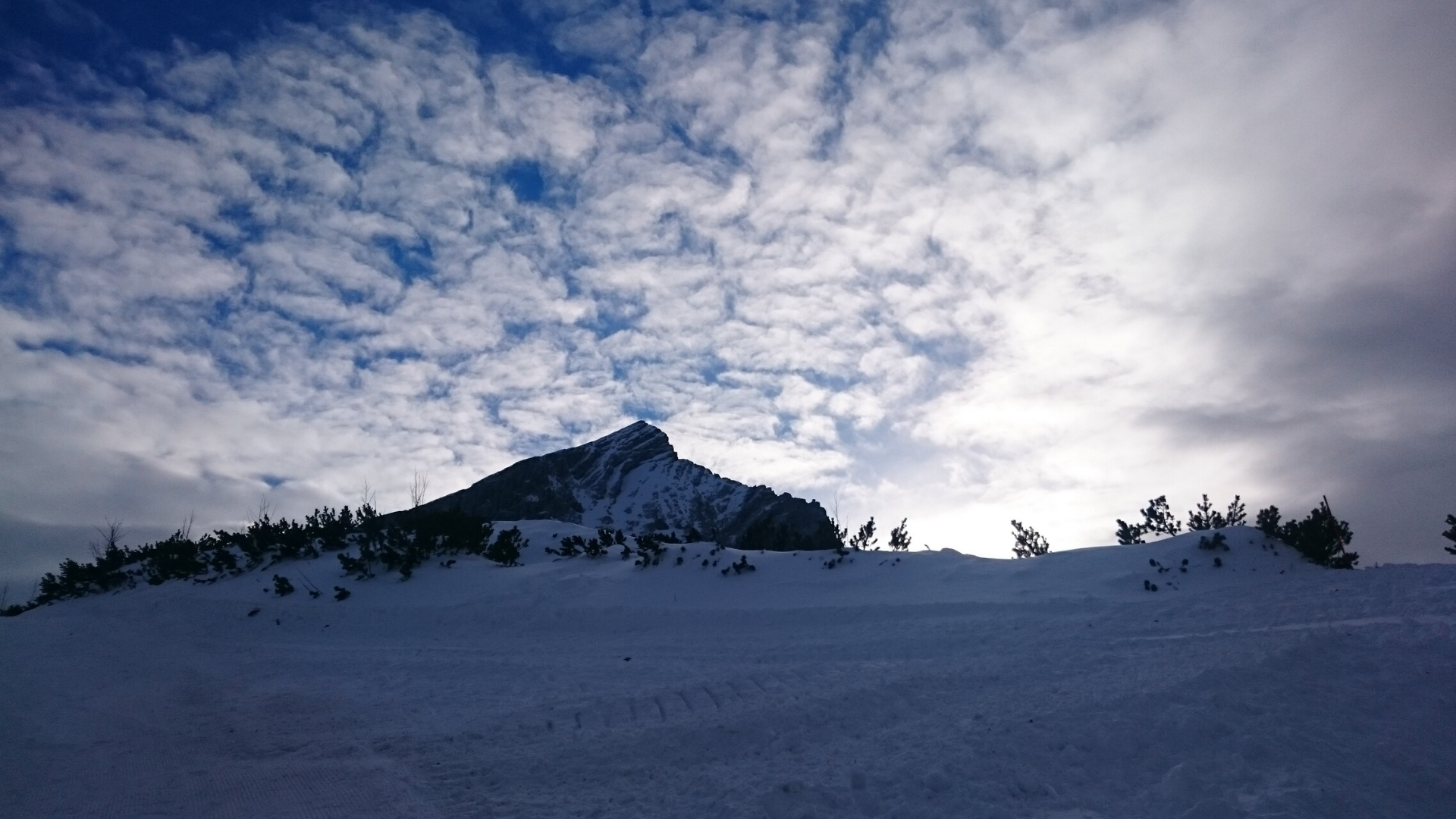 direkter unterhalb der Bergspitze, leichte Flockenwolken überall