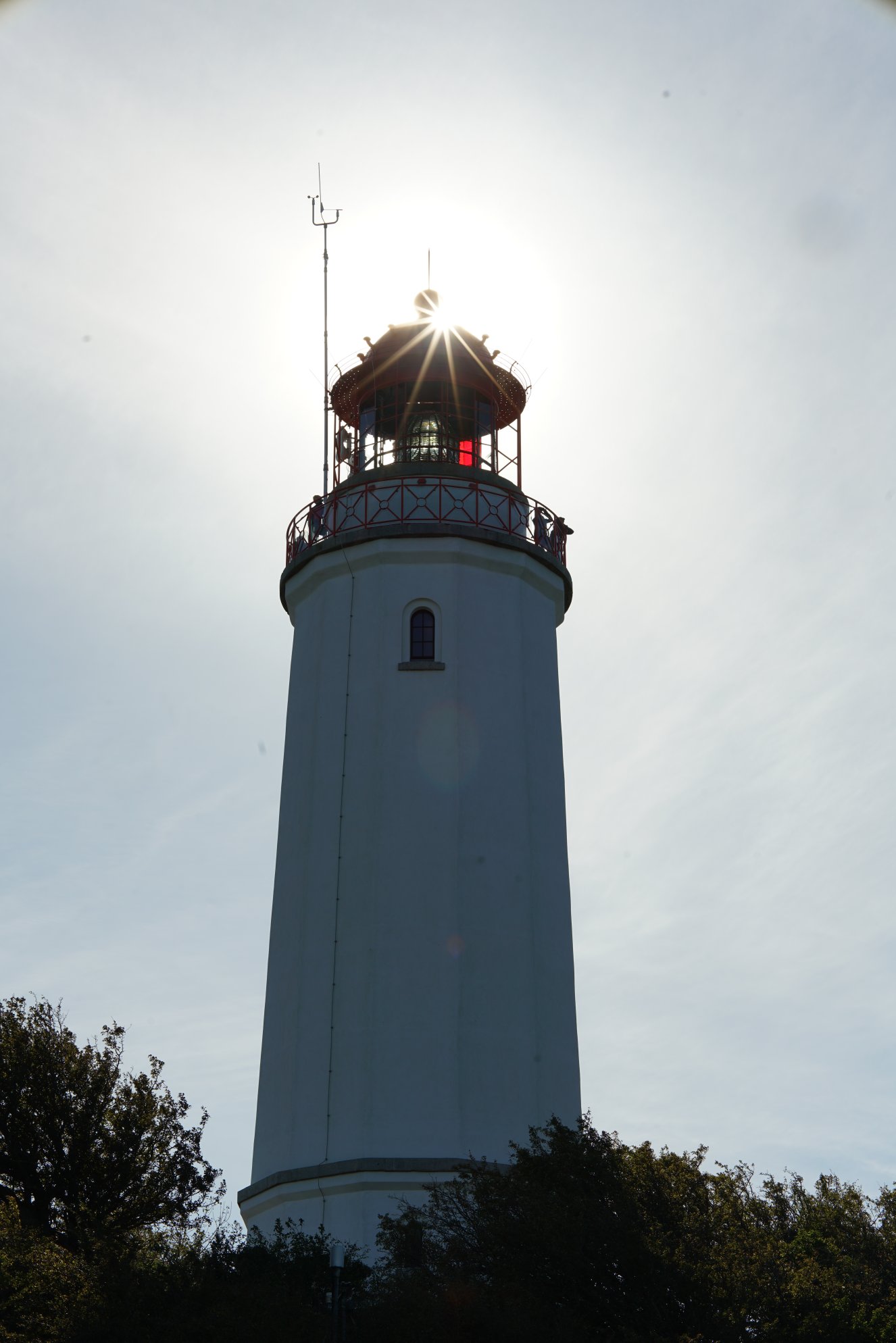 Leuchtturm von unten, Sonne hinter der Spitze, dadurch Sonnenstern im Bild 