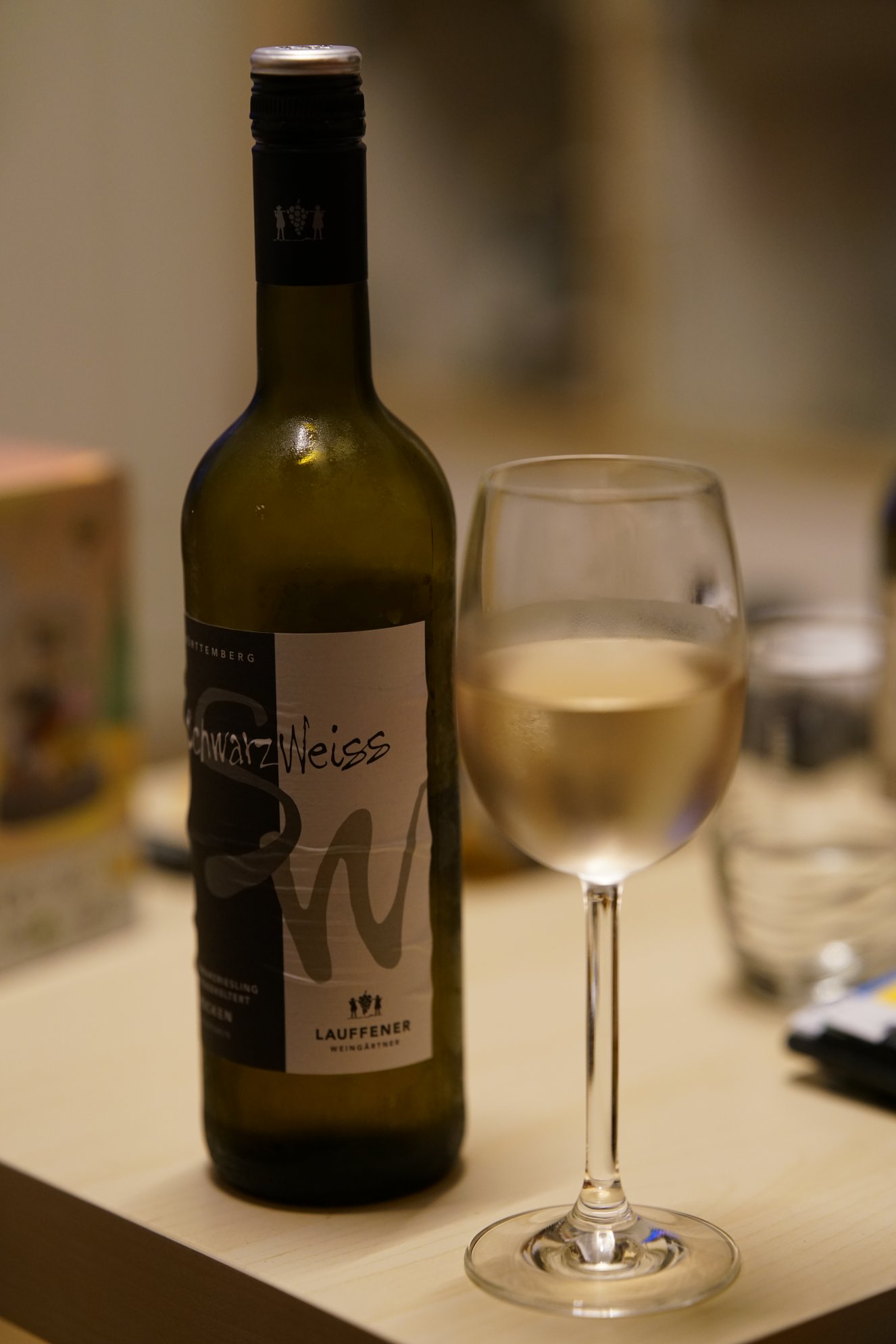 Flasche Wein, halbvoll, daneben gefülltes Glas 