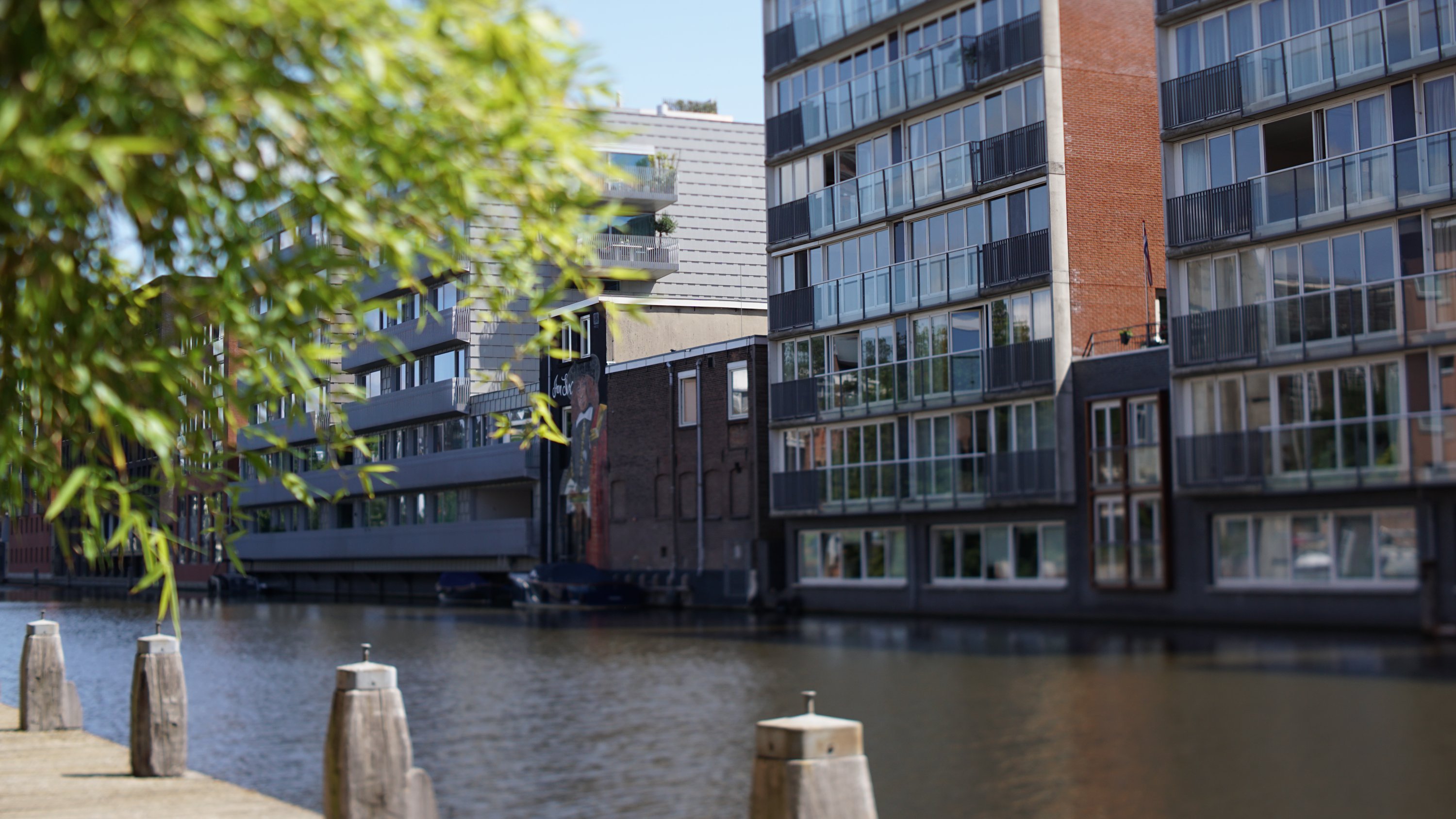 Anleger, Wasser einer ruhigeren Gracht, dahinter modernere Gebäude 