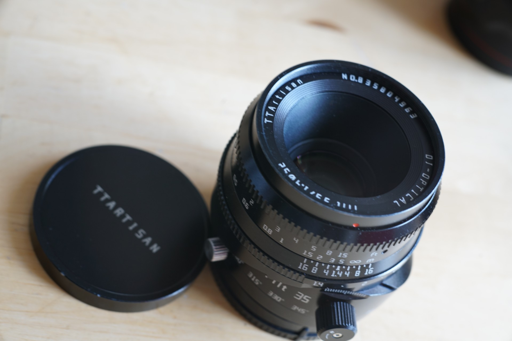 Das beschriebene Objektiv, in geknicktem Zustand, Deckel liegt daneben