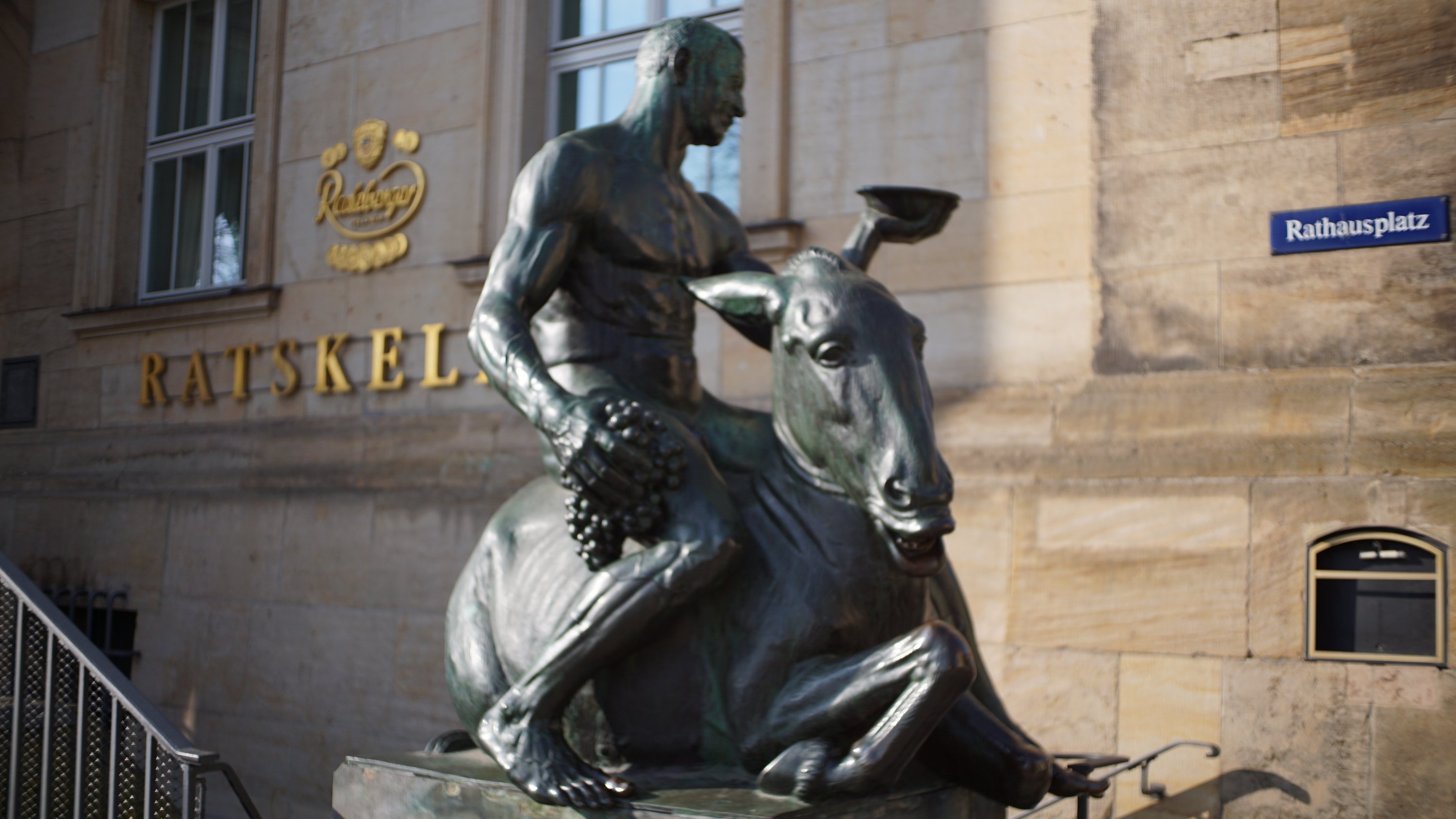 Statue vor dem Treppeneingang zum Ratskeller - Straßenschild Rathausplatz ganz rechts