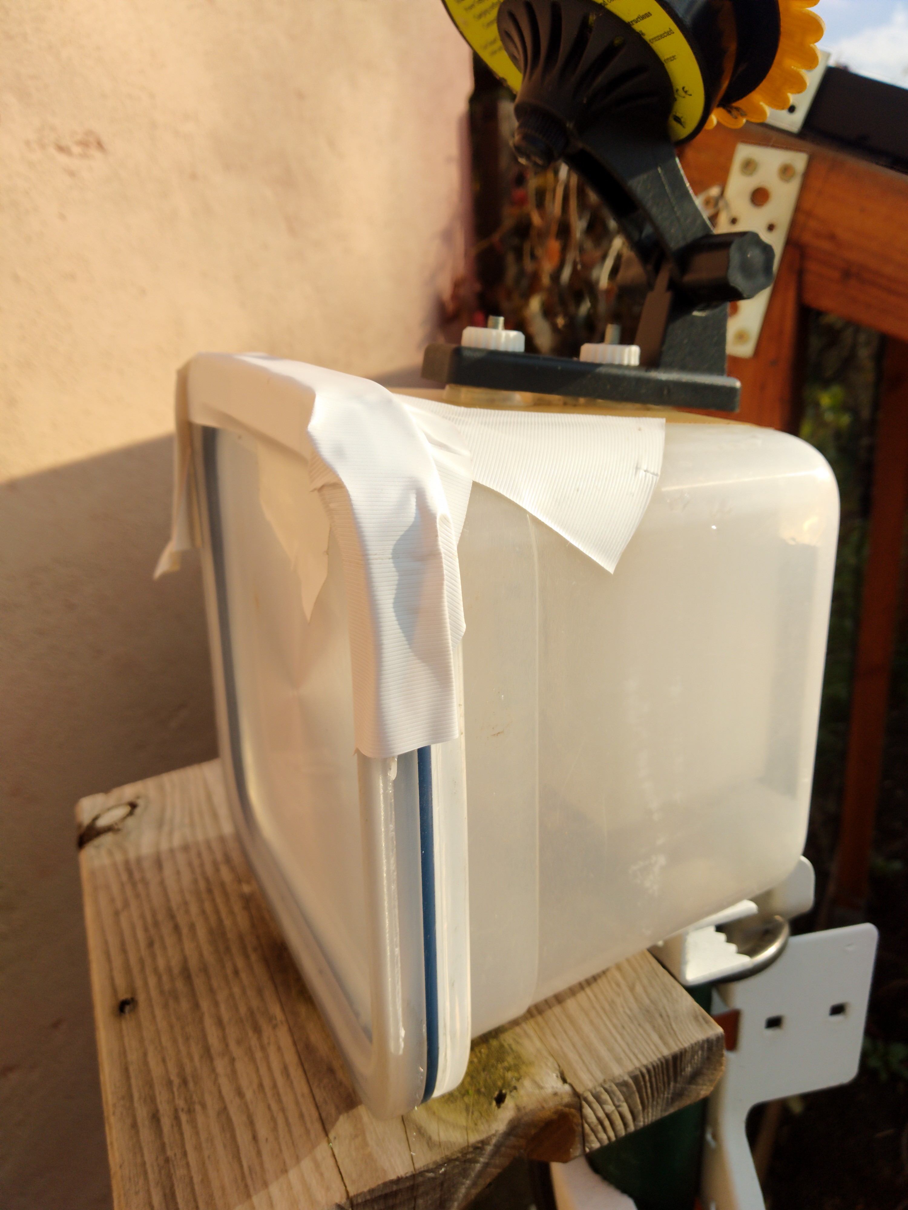 "tupper"-Dose mit Elektronik drin,  im Garten auf Holzbrett an Stange