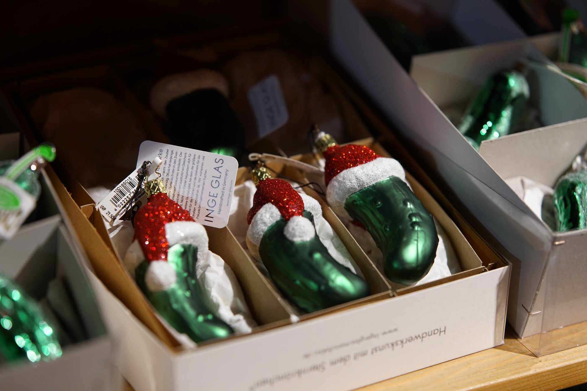 Grüne Gurken mit weihnachtlichen Mützen in Pappkartons