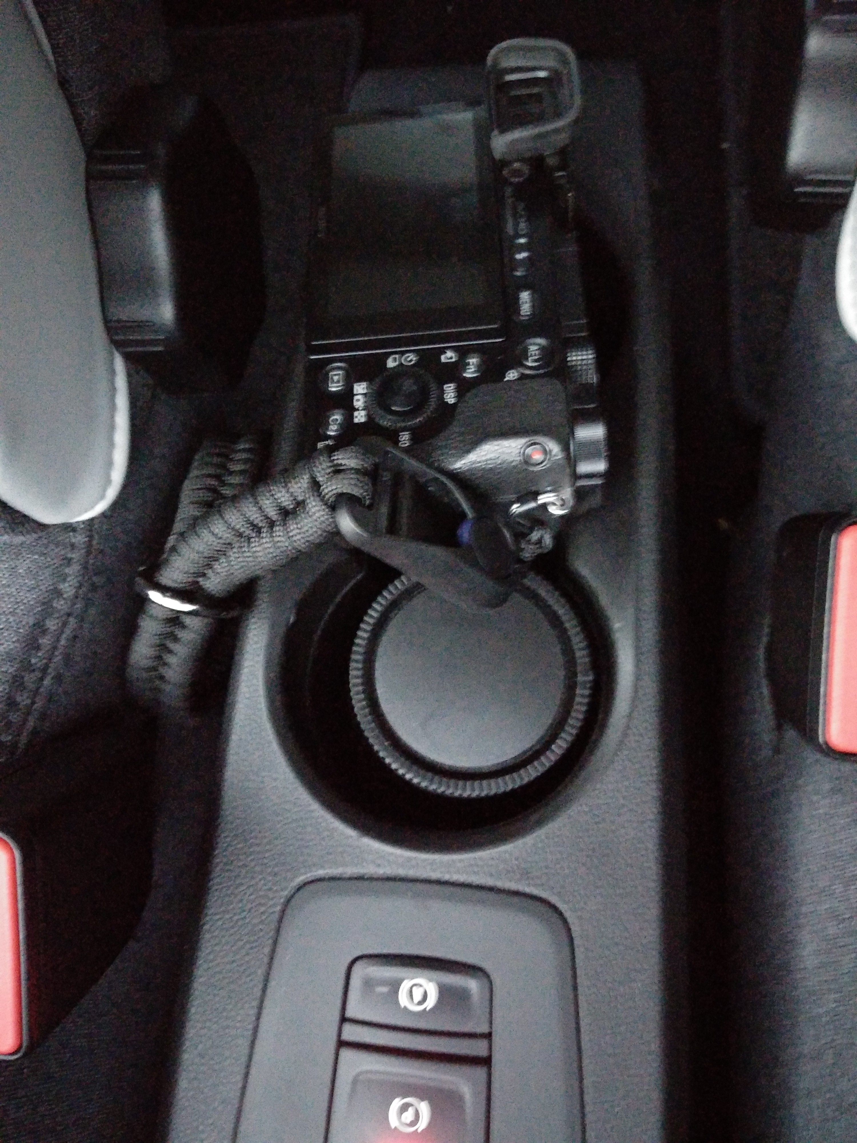 Sony Alpha Kamera und ein zusätzliches Objektiv stecken jeweils in einem Becherhalter der Mittelkonsole Sony Alpha Kamera und ein zusätzliches Objektiv stecken jeweils in einem Becherhalter der Mittelkonsole
