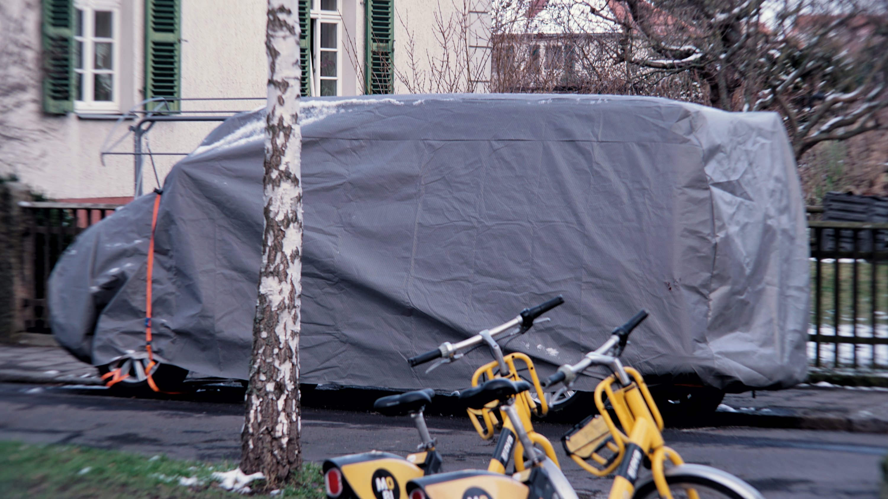 in Folie eingepackter Kleintransporter am Straßenrand eines Wohngebietes

2 Sharing-Fahrräder im Vordergrund