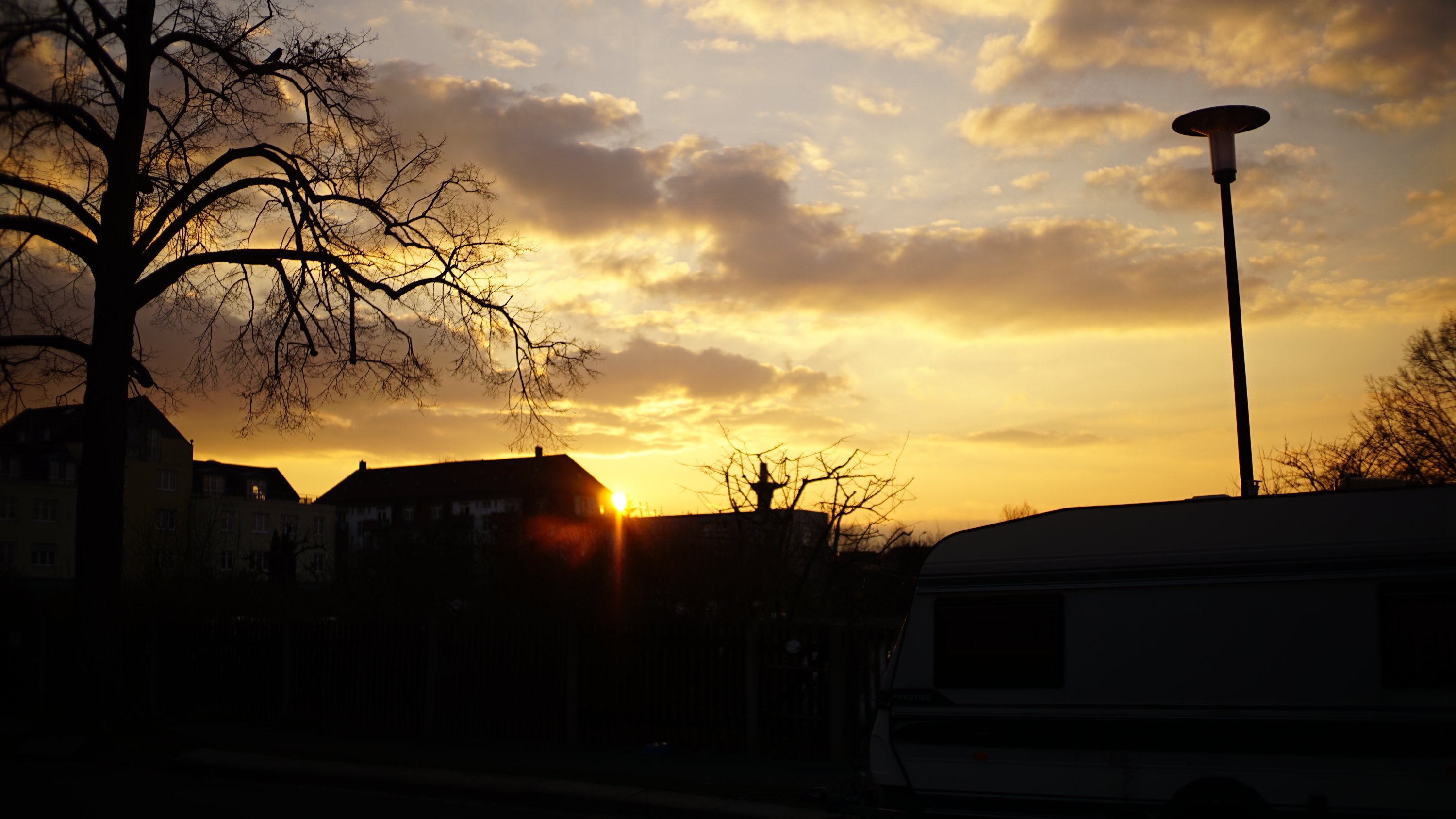 Sonne kurz vor Untergang, hinter Ecke eines Hauses