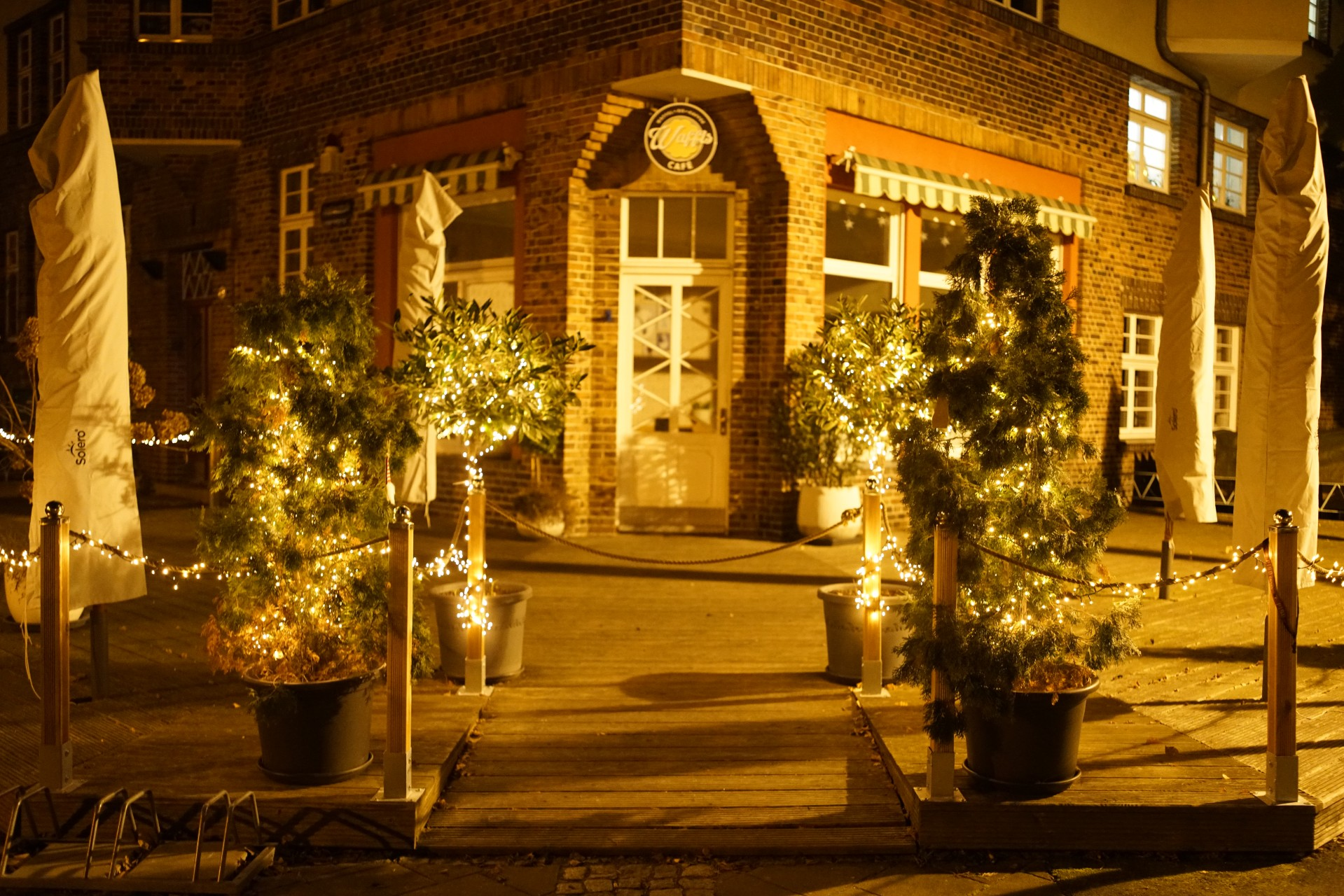 Haupteingang, eingerahmt von beleuchteten Pflanzkübeln