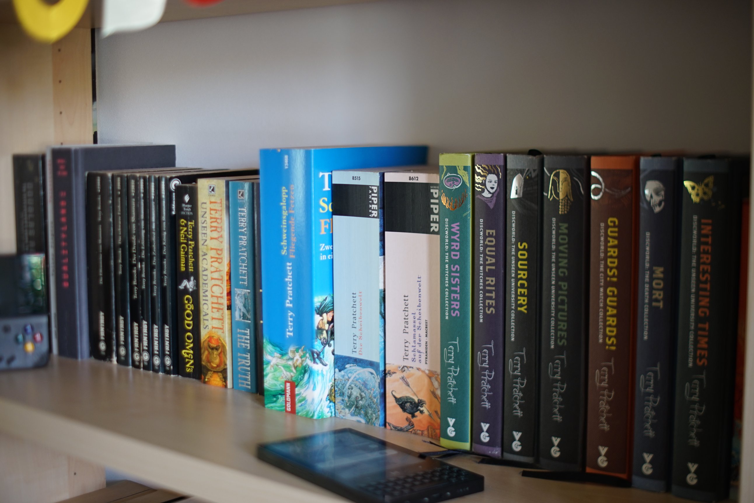 Bücher, davor Handheld-Spielekonsole im Gameboy-Format
Fokus-Ebene versucht auf die Bücherrücken zu schieben.