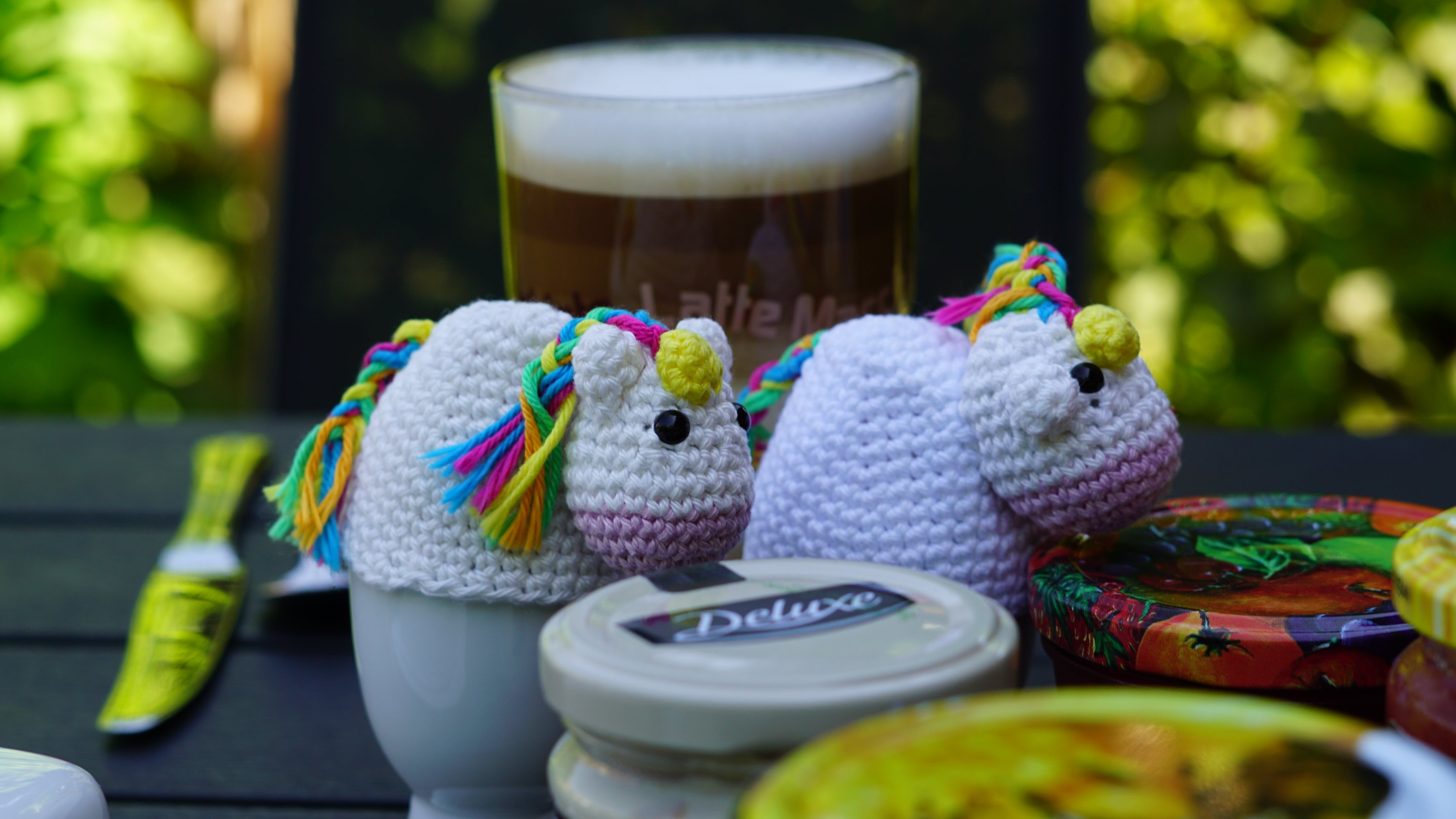 Zwei Einhorn-Eierwärmer in gehäkelt, auf dem Frühstückstisch 