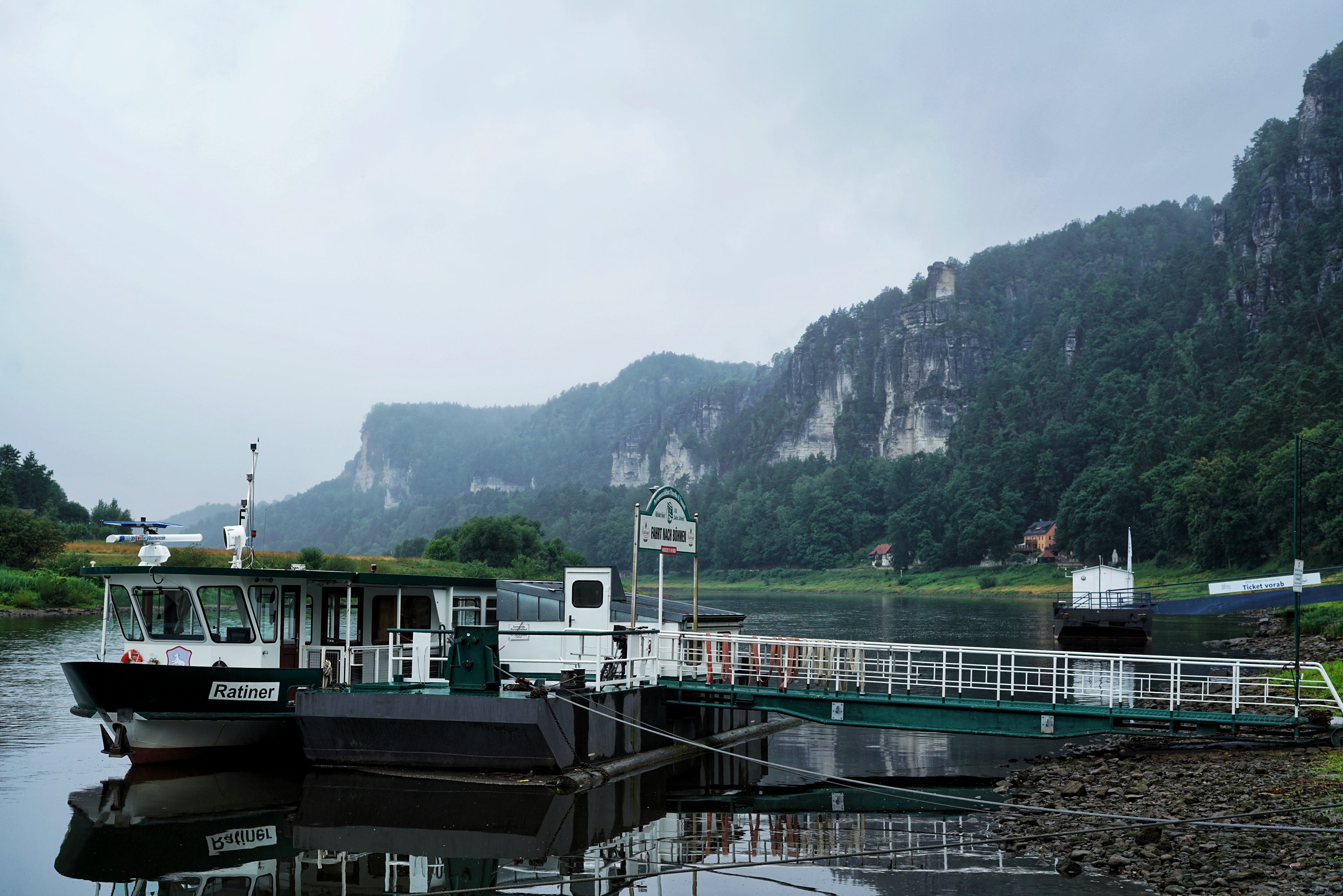 Fähre im Vordergrund, Elbsandsteingebirge mit Wald im Hintergrund 
Neblige Abendstimmung, Elbe ruhig und wellenlos