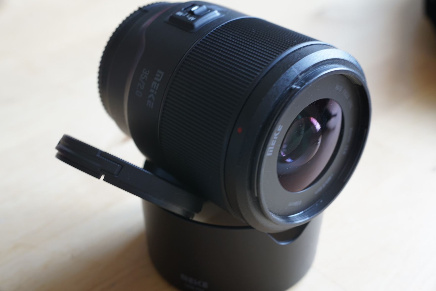 Meike Objektiv, auf Sonnenblende liegend, mit abgenommenem Deckel