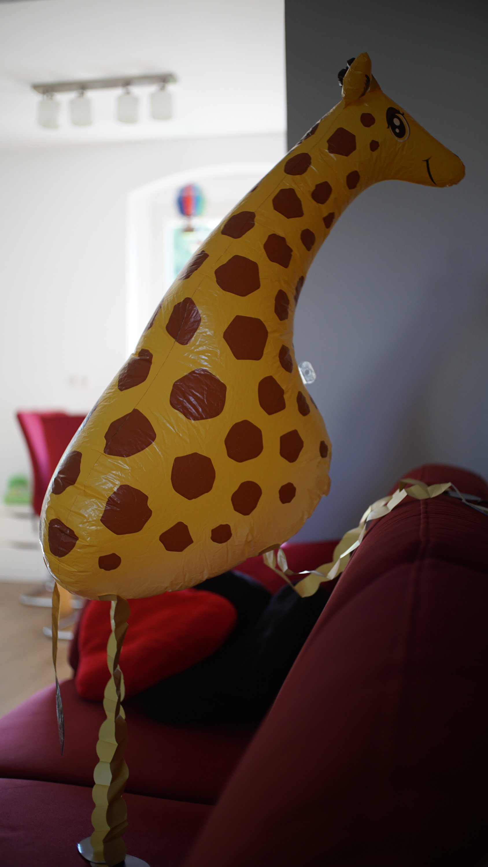 Giraffe auf Sofa, ein Bein auf der Lehne 