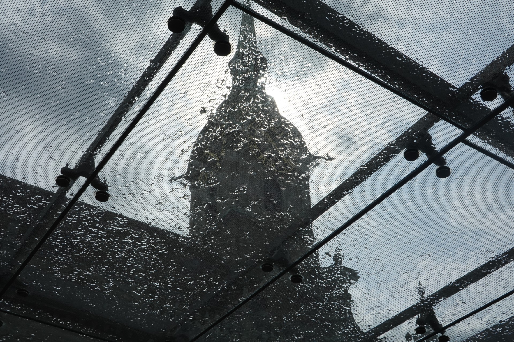 Glasdach, getragen von Metallstreben, darauf Wassertropfen, darüber Kirchturm und Wolen - Sonne hinter'm Kirchturm Glasdach, getragen von Metallstreben, darauf Wassertropfen, darüber Kirchturm und Wolen - Sonne hinter'm Kirchturm