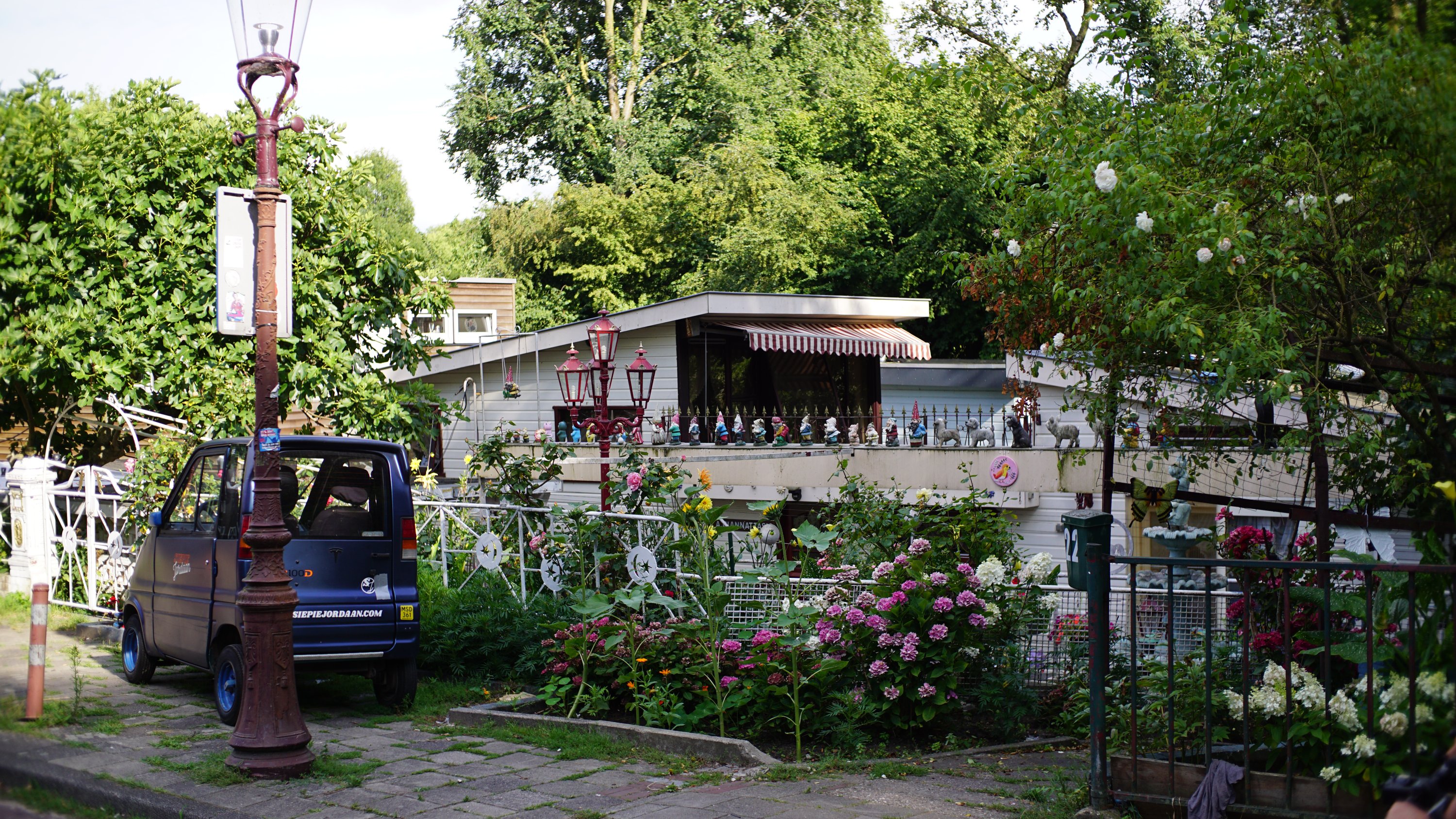 Hausboot mit Vorgarten, Gartenzwerge aufgereiht auf einer Brüstung 
25kmh-Möppel an der Laterne 