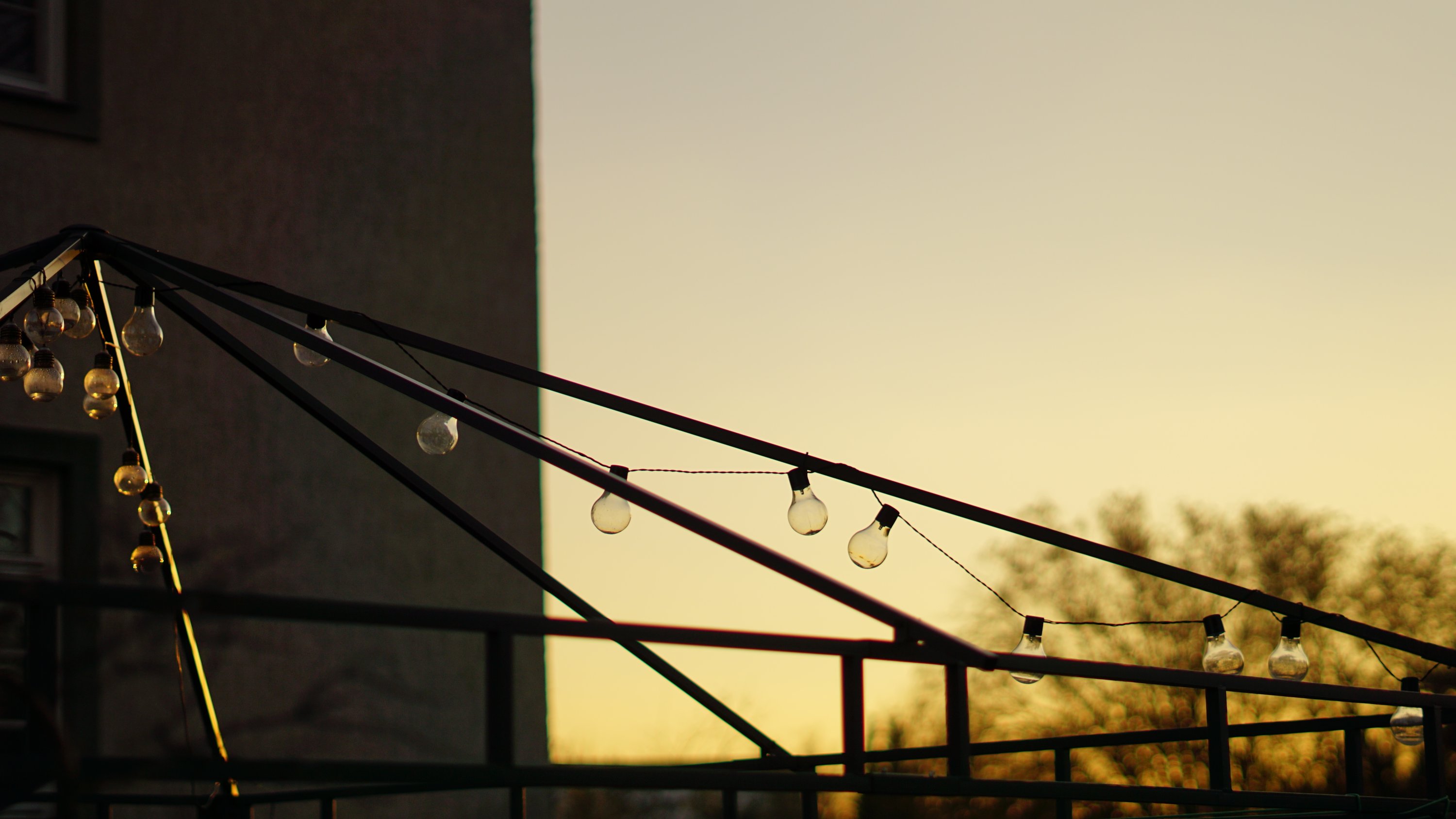 Glühlampen-Kette an Metallgestell im Gegenlicht des Sonnenuntergangs