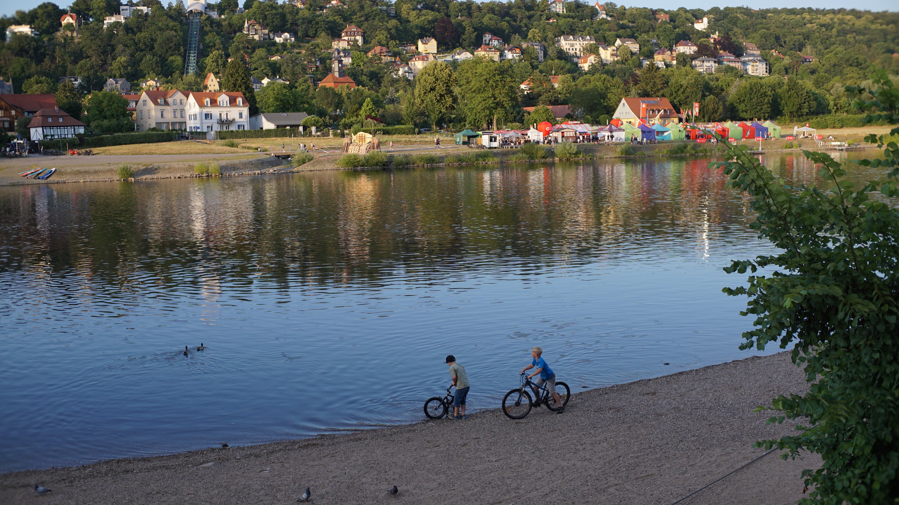 Kinder mit Fahrrad am Elbufer, Fest auf der gegenüberliegenden Seite 